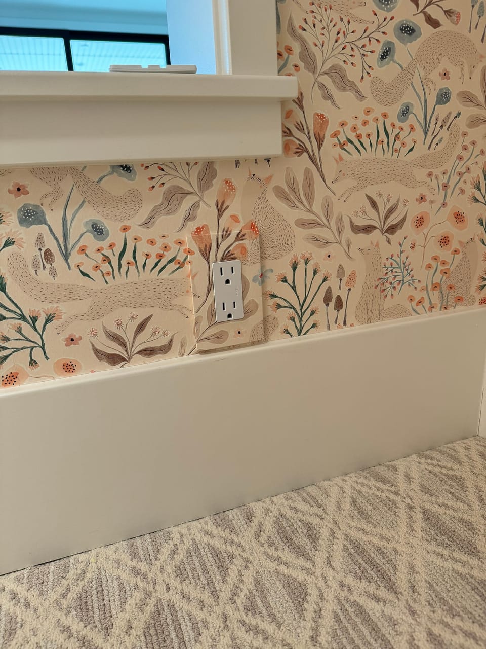 Floral paper on the playroom wall, with the outlet wrapped