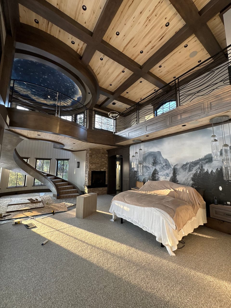 Mountain mural behind a bed under a coffered ceiling